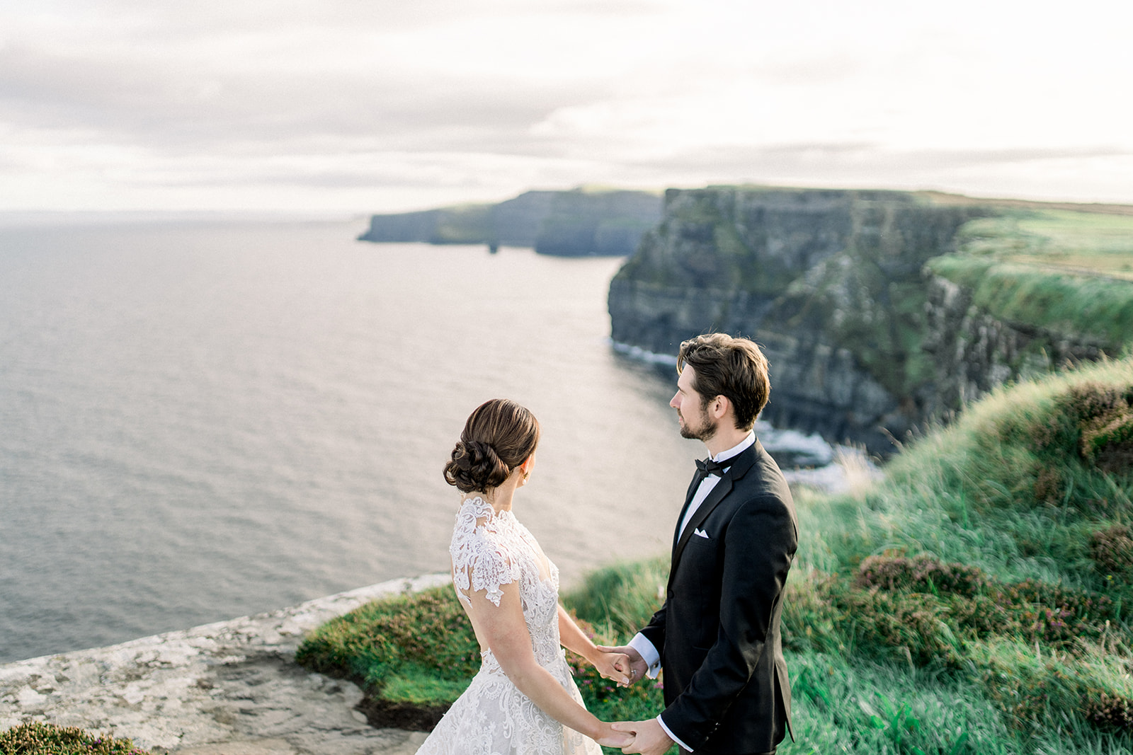 Bride and groom stand on the Cliffs of Moher at sunrise during their destination wedding elopement in Ireland.