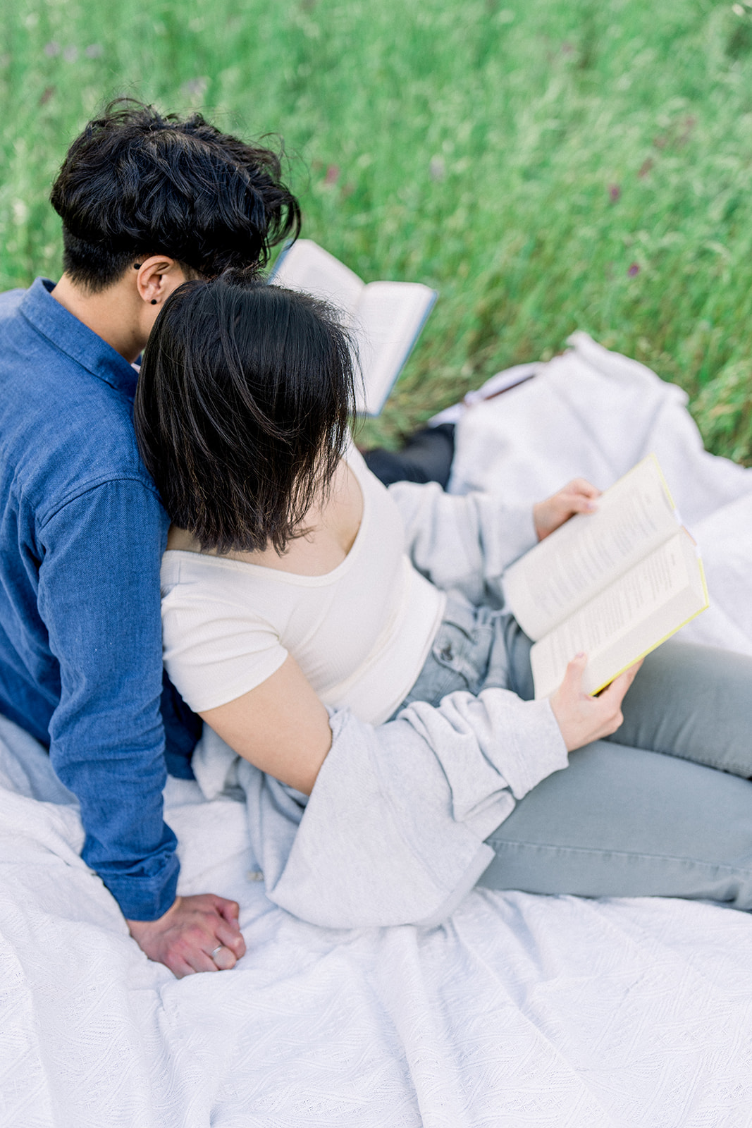 Couple enjoying a peaceful picnic, reading together in the lush green fields of Sunol Regional Wilderness, California.