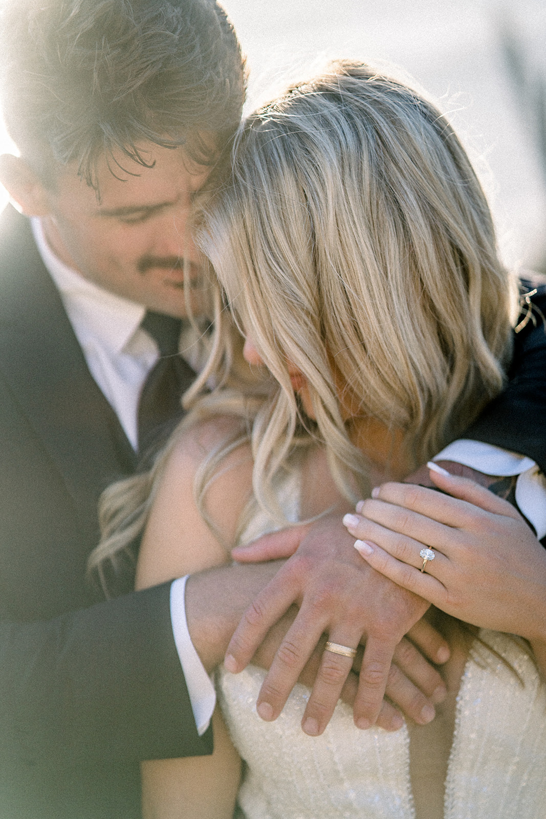 Pismo Beach wedding couple embracing with wedding rings glowing in the sunset.