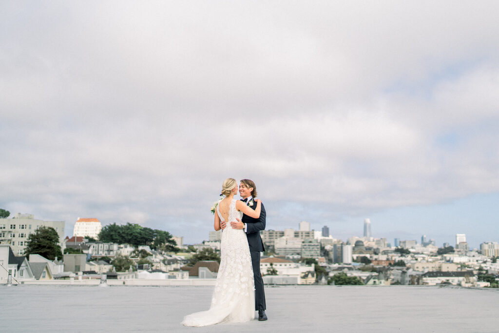 Bride and groom dancing on a rooftop with the San Francisco skyline in the background, capturing the city’s beauty at their San Francisco wedding.