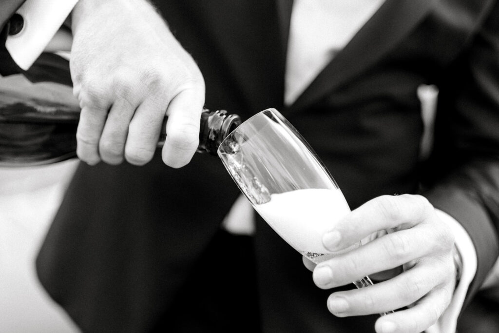 Pouring champagne to celebrate the San Francisco wedding reception in an elegant, black-and-white close-up shot.