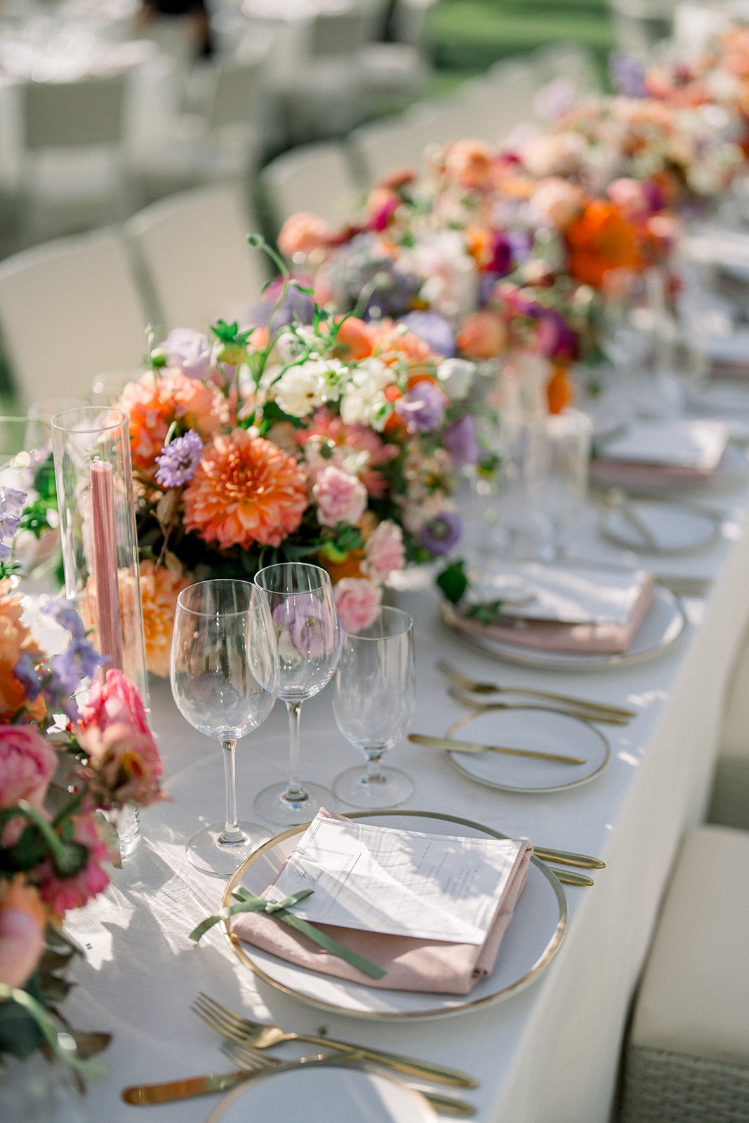 Elegant Carneros Resort wedding reception table with vibrant peach, coral, and lavender florals, velvet napkins, and gold-rimmed place settings at a Napa Valley outdoor celebration