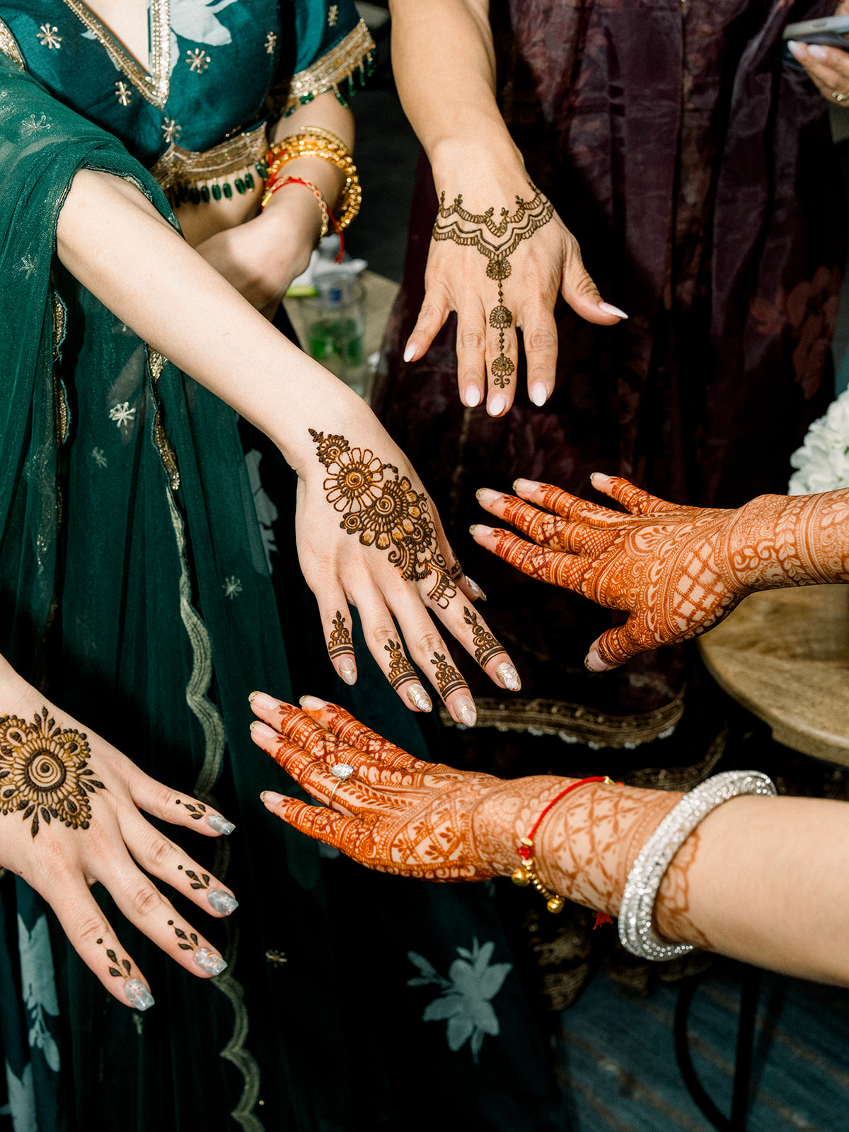 Several guests showing off fresh henna designs on their hands at a Sangeet and mehndi night at The Film Hub in Vista, California