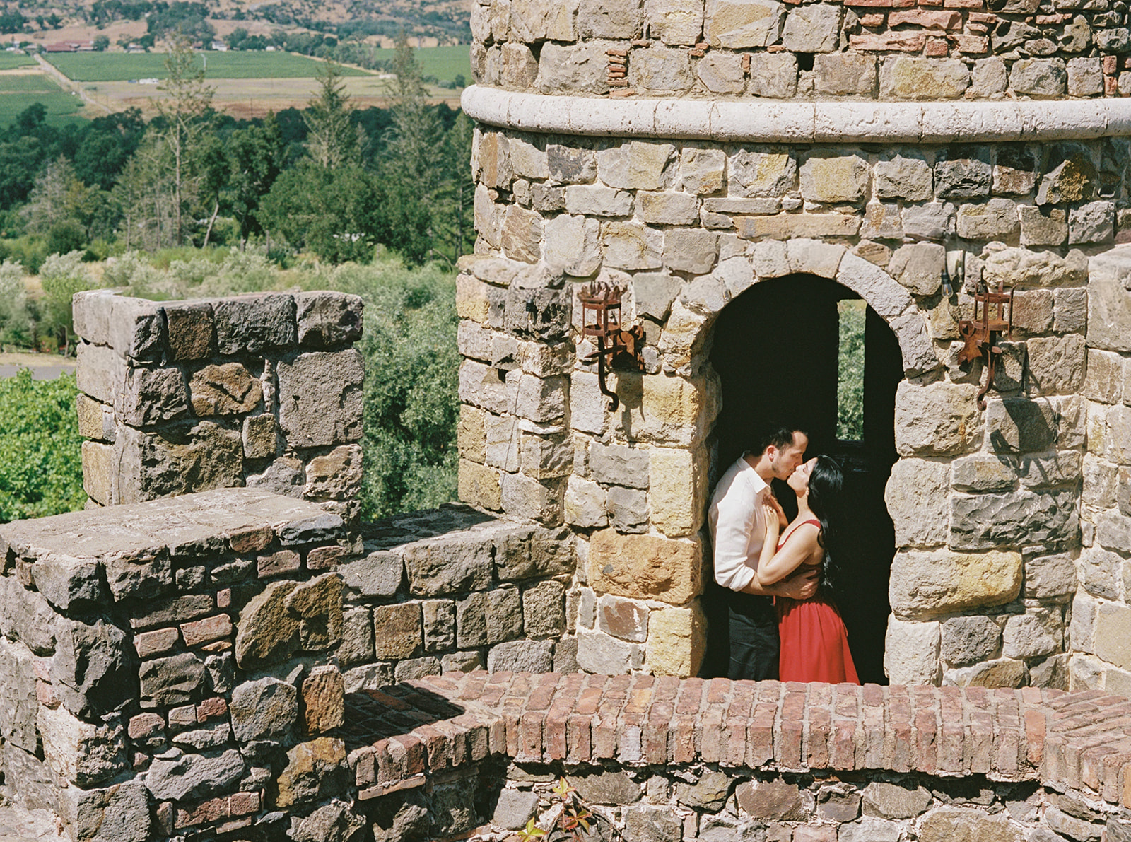 Donna and Daniel embracing in a stone archway at Castello di Amorosa during their Napa Valley proposal