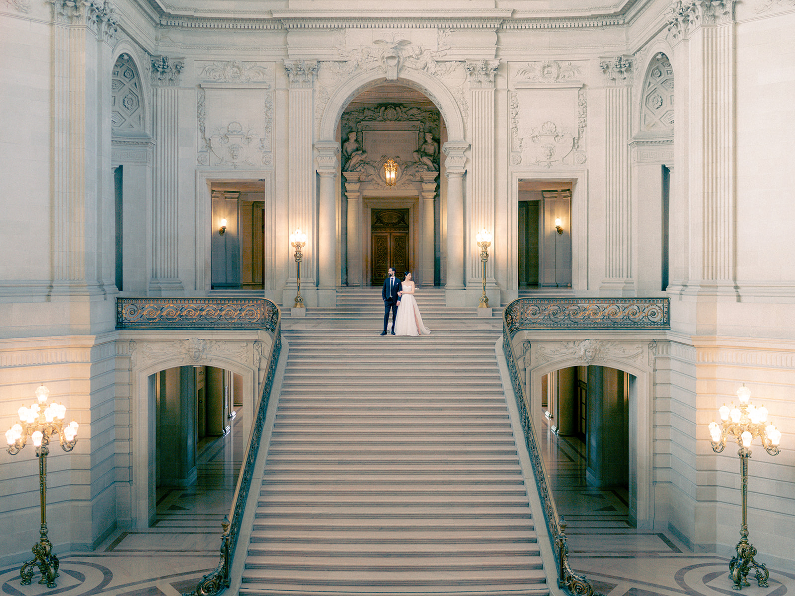 Bride and groom descending the grand staircase at San Francisco City Hall during their elopement
