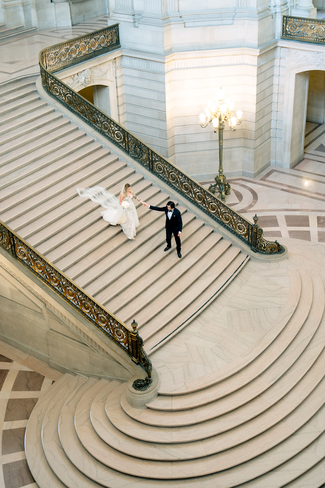 Overhead view of a bride and groom on the curved marble grand staircase at San Francisco City Hall