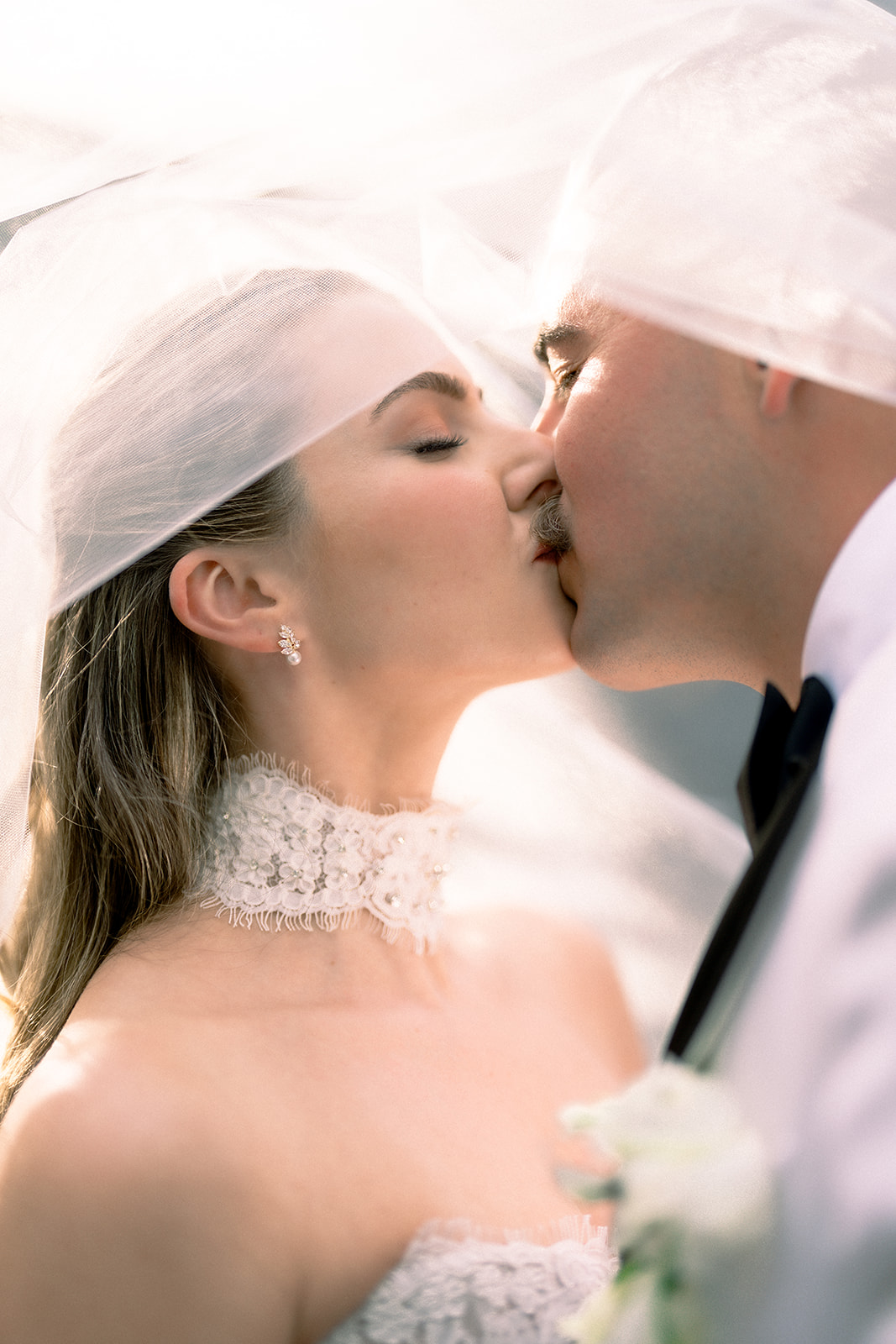 Couple sharing a kiss beneath the bride’s veil at their Evergreen Lodge Yosemite wedding